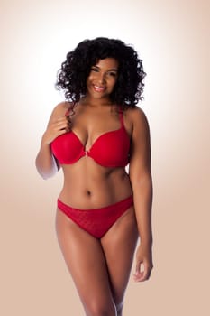 Beautiful happy plus size sexy woman with curly hair in red lingerie bra and thong underwear.