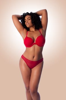 Beautiful happy plus size sexy woman with curly hair in red lingerie bra and thong underwear.