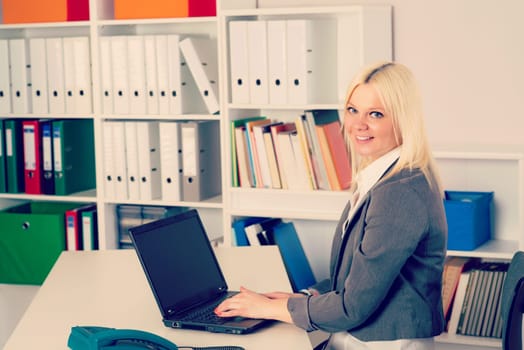 young blond business woman in the office looking friendly in to the camera