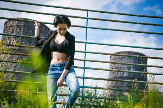 young woman dressed in white sneakers, black top and blue jeans, on a background of urban landscapes. Street fashion