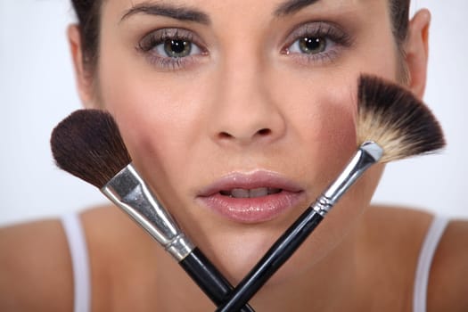 Closeup of a woman with makeup brushes