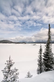 Upper Kananaskis Lake in winter framed by trees.