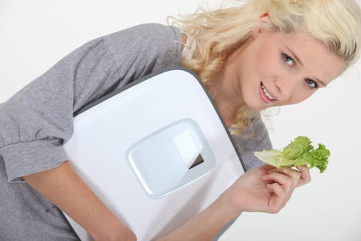 Woman holding a scale and a lettuce leaf