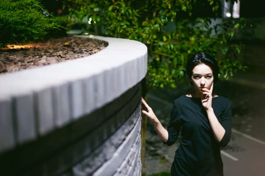 young woman with beautiful feet dressed in white sneakers and black dress, against a backdrop of urban landscapes. Street fashion. night dark style