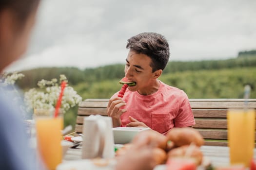 Teenage boy sitting outside and eating fruit.