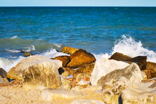 white rocks hit by large foamy waves on a sunny day