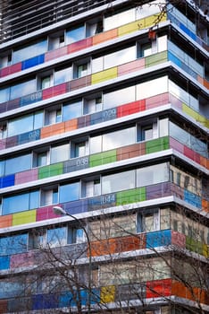 Bottom view of a modern building with colored and numbered glass balconies.