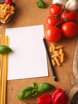 Pasta or Italian food concept background with an empty paper sheet and pencil on a wooden table