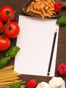 Pasta or Italian food concept background with an empty paper sheet and pencil on a wooden table
