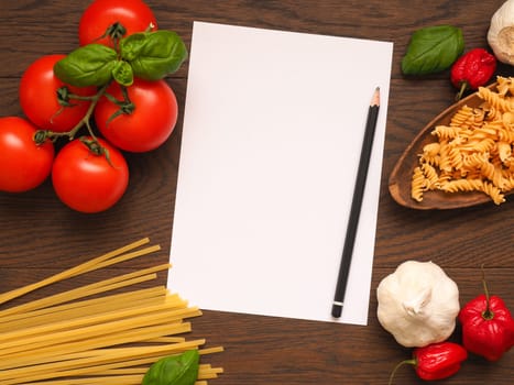 Pasta or Italian food concept background with an empty paper sheet and pencil on a wooden table