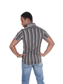 A young African American man in a striped shirt and jeans standing from .the back looking down with hands on hip, isolated for white background.