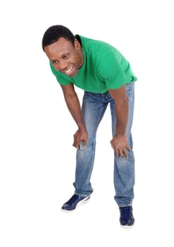 A happy smiling African American man standing in a green polo shirt.and jeans bending forwards, isolated for white background.