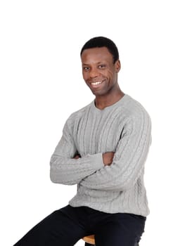 A happy and handsome African American man sitting with his arms.crossed in a gray sweeter, isolated for white background.