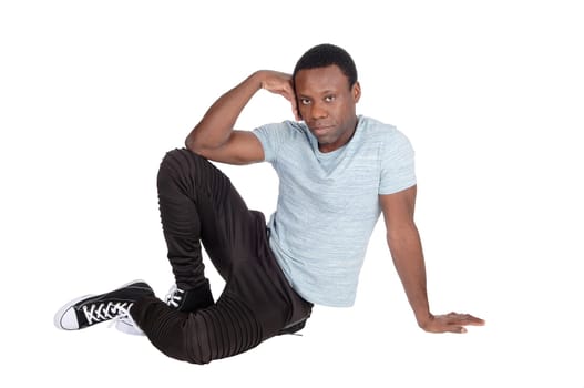 A young good looking African American man sitting on the floor,.resting, with his hand on his head, isolated for white background.