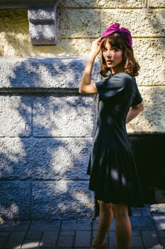 Beautiful woman in a dark stylish dress strolls along the street, near boutiques. Portrait of a fashionable girl