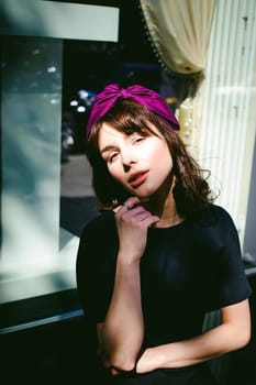 Beautiful woman in a dark stylish dress strolls along the street, near boutiques. Portrait of a fashionable girl