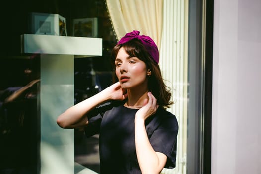 Beautiful woman in a dark stylish dress strolls along the street, near boutiques. Portrait of a fashionable girl