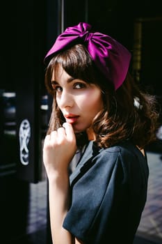 Beautiful woman in a dark stylish dress strolls along the street, near boutiques. Portrait of a fashionable girl