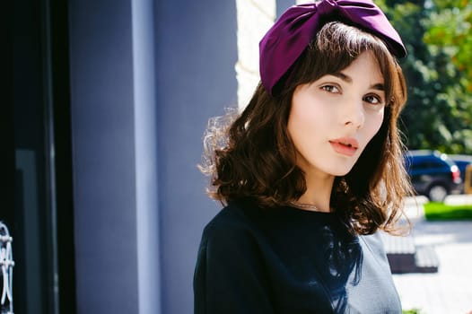 Beautiful woman in a dark stylish dress strolls along the street, near boutiques. Portrait of a fashionable girl