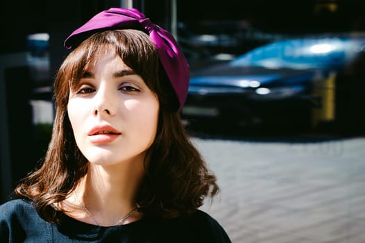 Beautiful woman in a dark stylish dress strolls along the street, near boutiques. Portrait of a fashionable girl