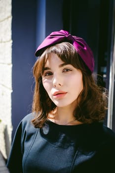 Beautiful woman in a dark stylish dress strolls along the street, near boutiques. Portrait of a fashionable girl