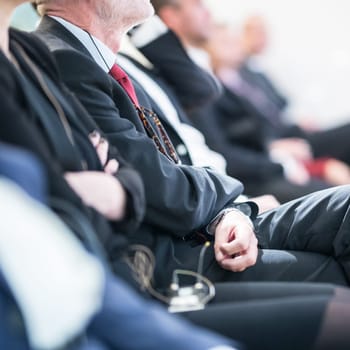 Row of unrecognizable business people sitting in conference hall at business event. Audience at business seminar. Business and Entrepreneurship concept.