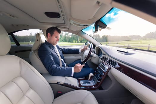 Businessman using cell phone and texting while driving not paying attention to the road.