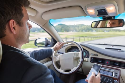Businessman using cell phone and texting while driving not paying attention to the road. Dangerous texting and driving at the same time