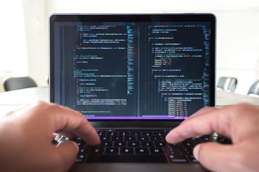 Programmer profession - man writing programming code on laptop computer. Code on screen is my property and can be seen as part of this photo.