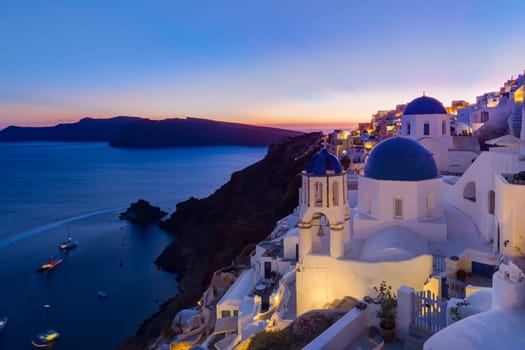 Cityscape of Oia, traditional greek village with blue domes of churches, Santorini island, Greece at dusk.