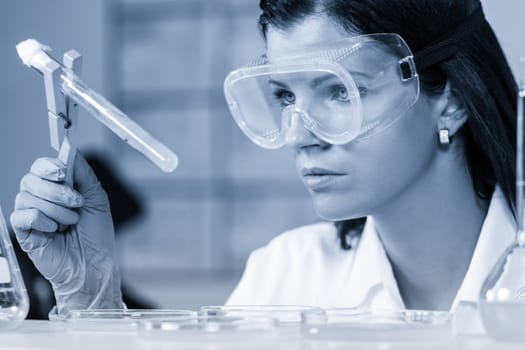 Health care professional researching in scientific laboratory. Female scientist observing bacterial colonies in glass tube in life science research laboratory. Biochemistry, genetics, microbiology...