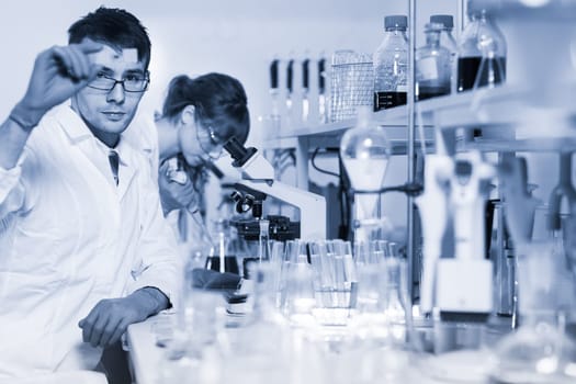Health care researchers working in life science laboratory. Young researchs preparing and analyzing microscope slides in research lab.