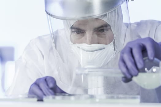 Life scientist researching in bio hazard laboratory. Focused life science professional working on experiment in high protection degree work laboratory. Healthcare and biotechnology.
