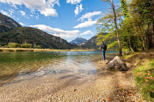 Hiker standing on the shore of the lake among the mountains admiring the landscape.