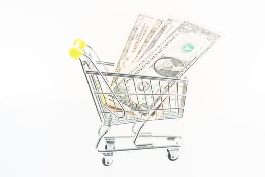 Miniature shopping cart with US one, five, ten and fifty dollar banknotes