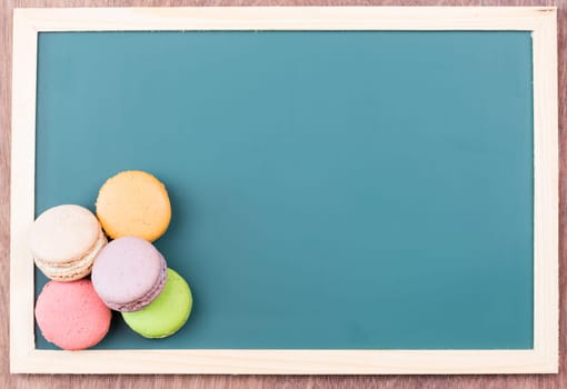 Macarons on green chalkboard top view