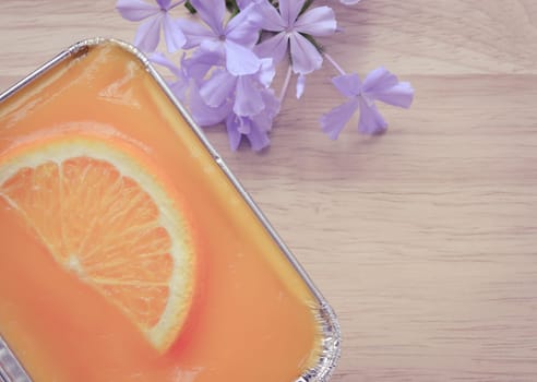 Orange soft cake with sliced orange fruit in aluminum foil tray on wooden background. Retro-Vintage filter effect