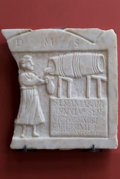 Merida, Spain - December 20th, 2017: Stela of Sentia Amarantis. Tombstone showing a tavern keeper tapping wine from a barrel at National Museum of Roman Art in Merida, Spain