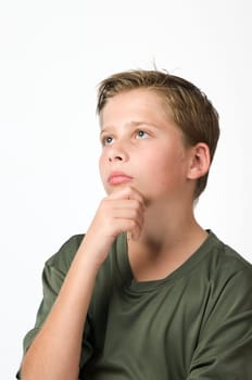 Lateral head and shoulder view of a young male teenager against a white background looks up with his hand on his chin.