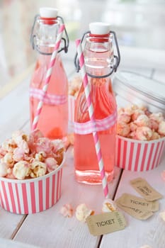 Colorful popcorn in striped cups and lemonade in small bottles