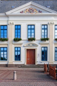 Esens,Germany - October 05,2016: Frontal view of the entrance area of the town hall in Esens with parts of the window front in classicist architectural style with golden decorations.
