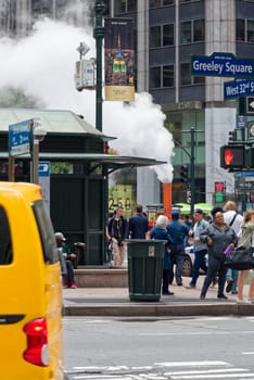 New York, NY, USA - June 06, 2015:Steam coming out of Greeley Square and the intersection West 32 in Manhattan in the spring. Traffic of cars and crowds of people.