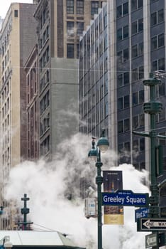New York, NY, USA - June 06, 2015:Steam coming out of Greeley Square and the intersection West 32 in Manhattan in the spring. Traffic of cars and crowds of people.