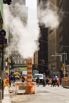 New York, NY, USA - June 06, 2015:Steam coming out of Greeley Square and the intersection West 32 in Manhattan in the spring. Traffic of cars and crowds of people.