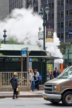 New York, NY, USA - June 06, 2015:Steam coming out of Greeley Square and the intersection West 32 in Manhattan in the spring. Traffic of cars and crowds of people.