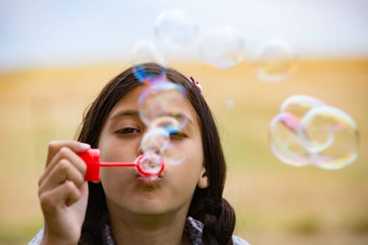 Child makes soap bubbles in the garden