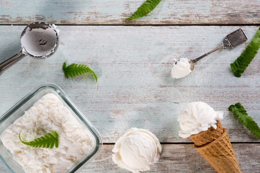 Top view milk ice cream wafer cone on white rustic wooden background. Copy space in middle.