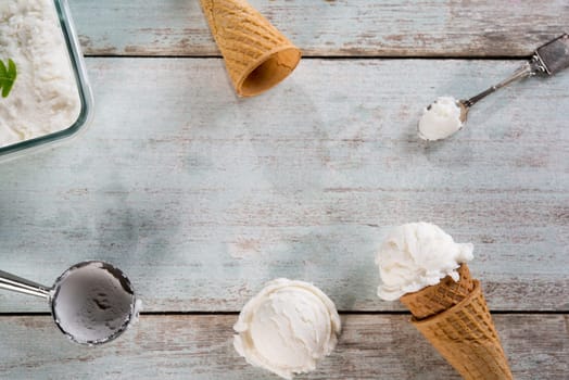 Top view vanilla ice cream wafer cone on white rustic wooden background. Copy space in middle.