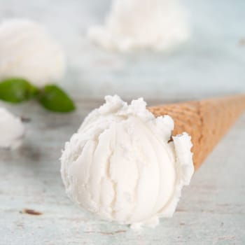 Milk ice cream wafer cone on white rustic wooden background