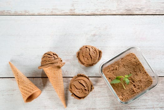 Top view chocolate ice cream in waffle cone on old rustic vintage wooden background. Copy space on above.